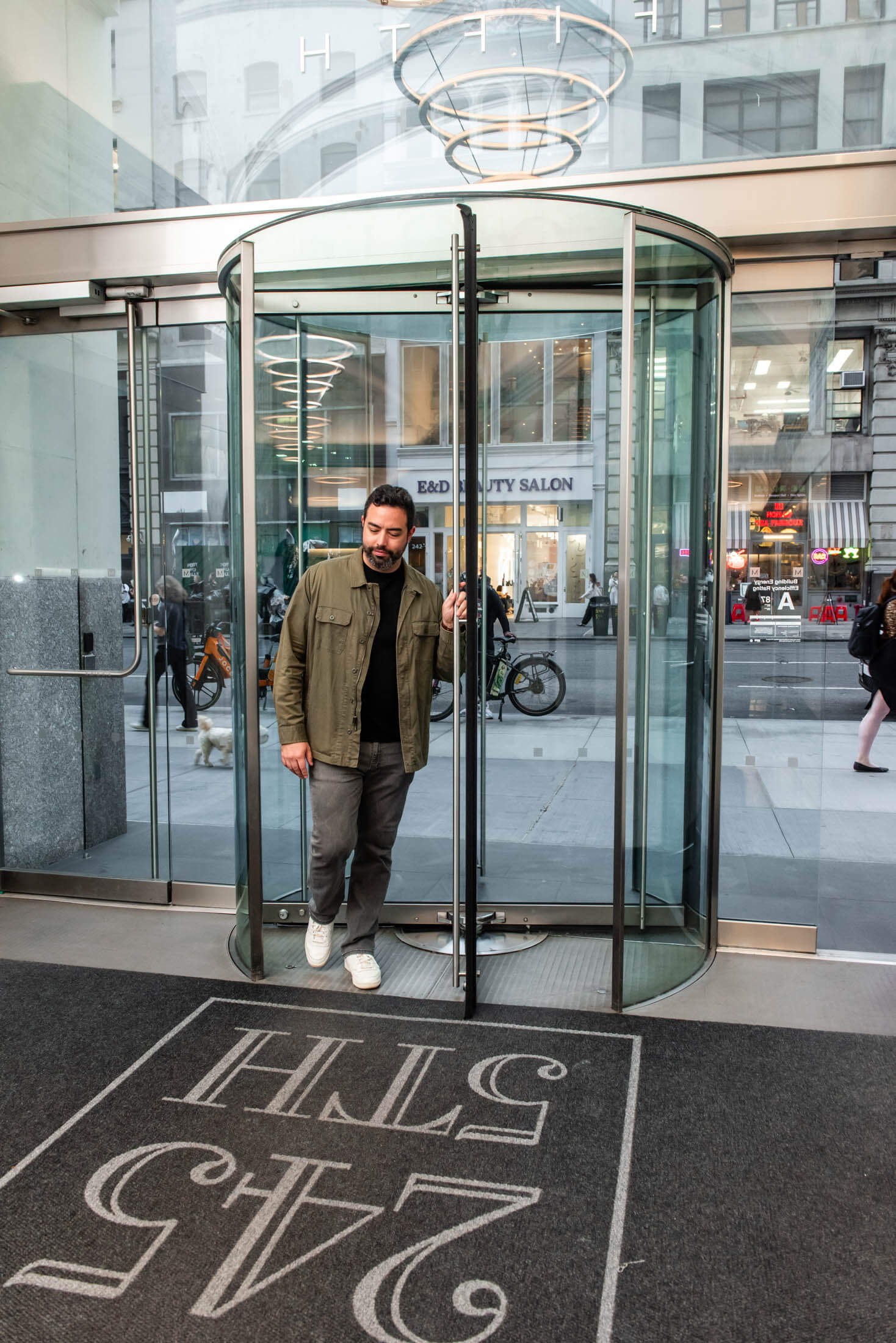 Man exiting through glass revolving door.