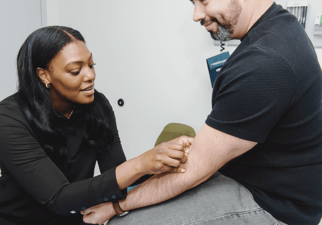 Healthcare professional examining patient's arm.